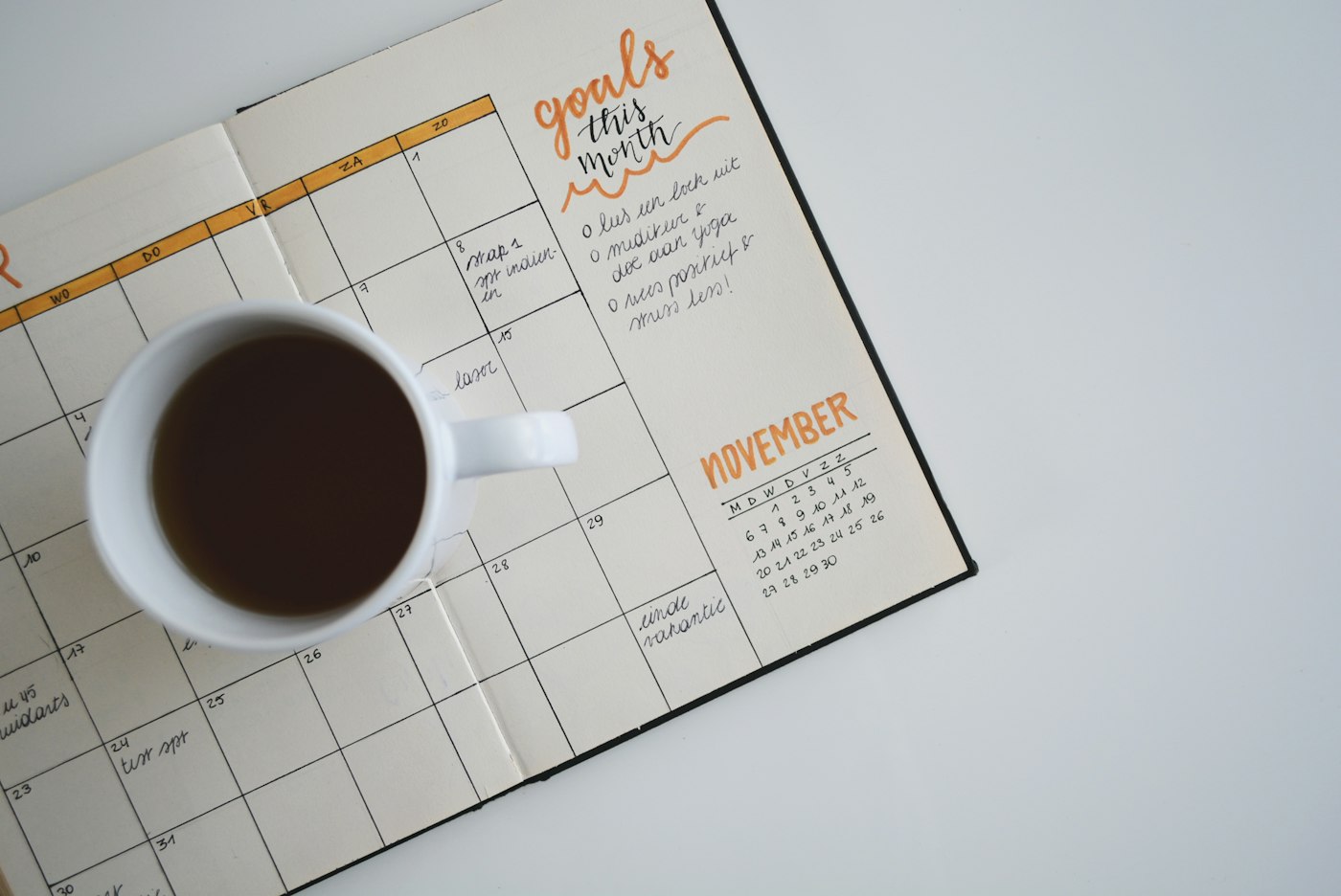 Una taza de café sobre una agenda mensual abierta